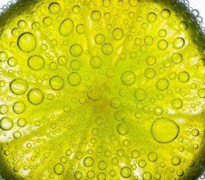 Close-up of air bubbles covering slice of juicy lime floating in water
